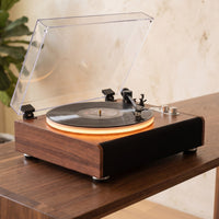 Platine vinyle Sillage avec éclairage de plateau allumé, posée sur une console en noyer